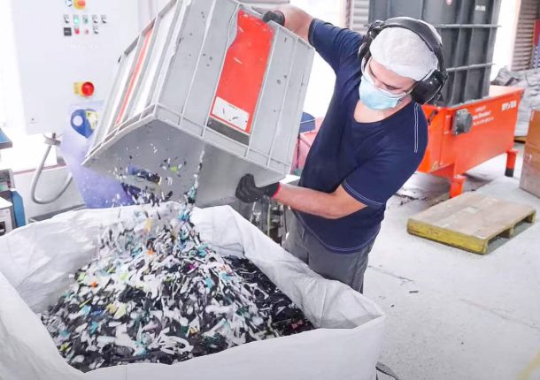 An employee dumps post-shredded plastic material into a gaylord for granulating.