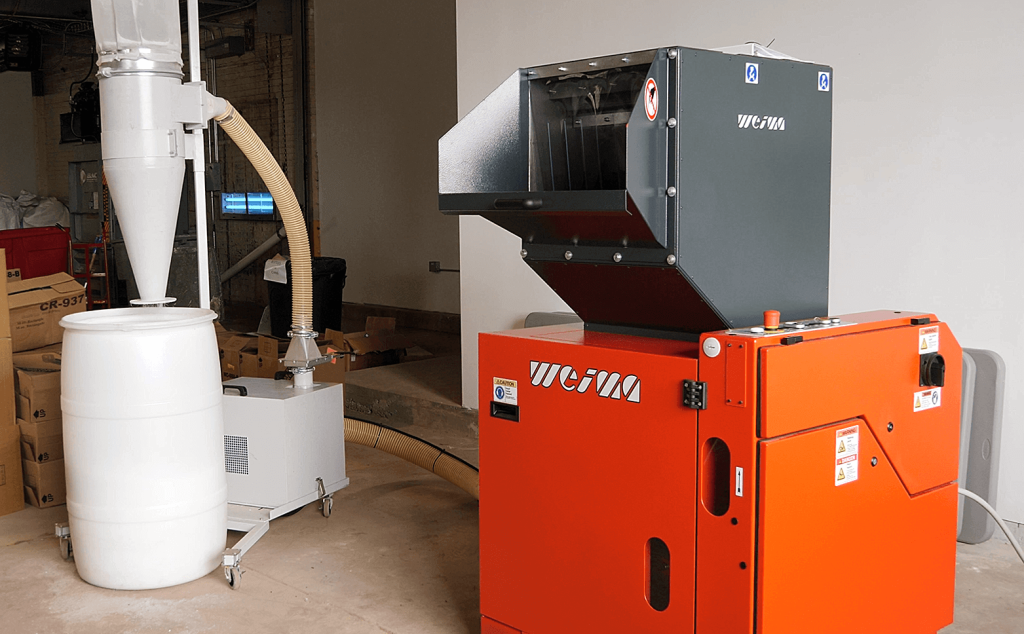 a WEIMA granulator is connected to an air system that discharges into a plastic drum