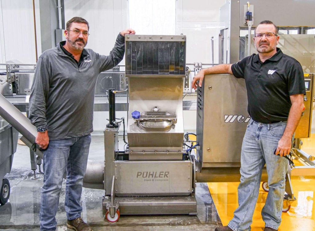 Two WEIMA employees next to WEIMA PUEHLER press E.200 in America