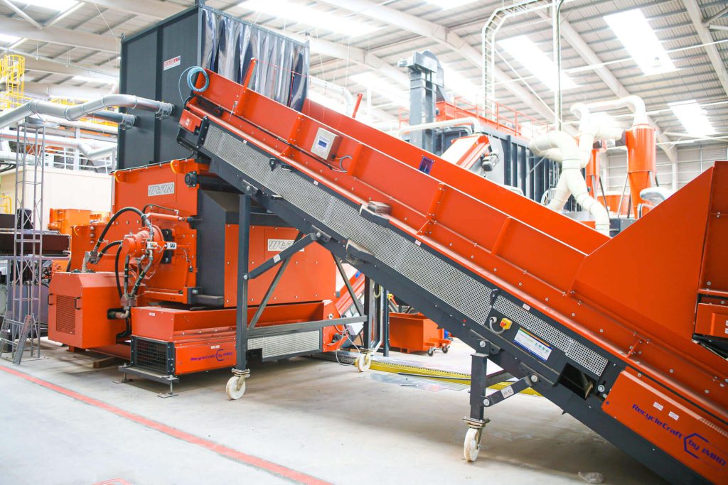 orange red weima plastic shredder with conveyor belts in production hall in england