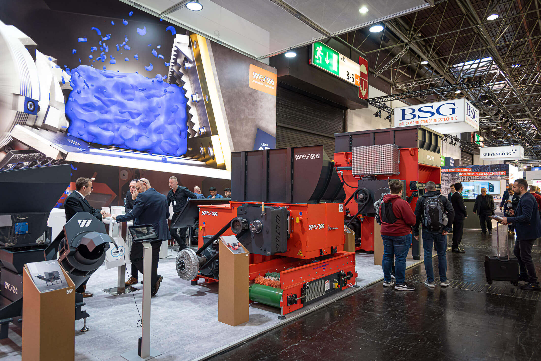 orange weima shredder in on K show booth surrounded by visitors