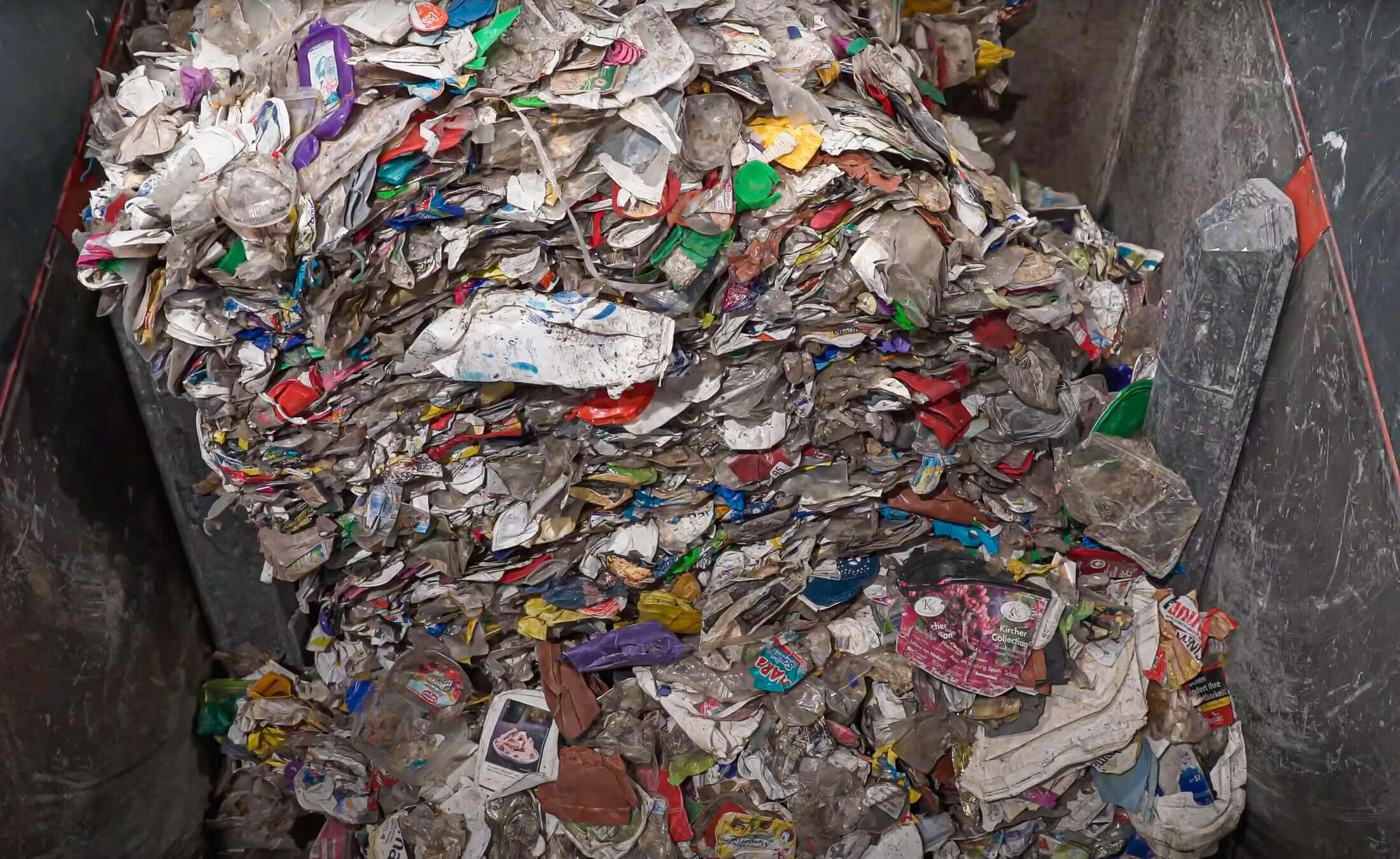 mixed post consumer packaging waste inside a weima shredder hopper