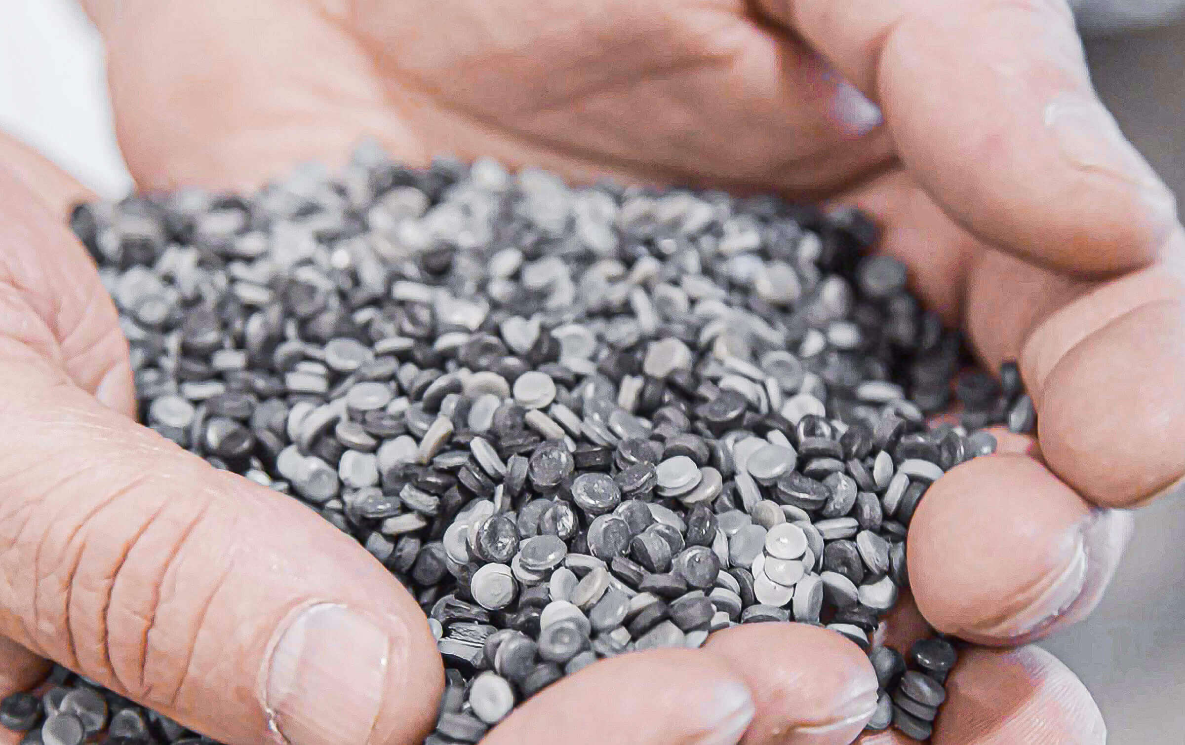 Secondary plastic raw material granulates inside a palm of a hand