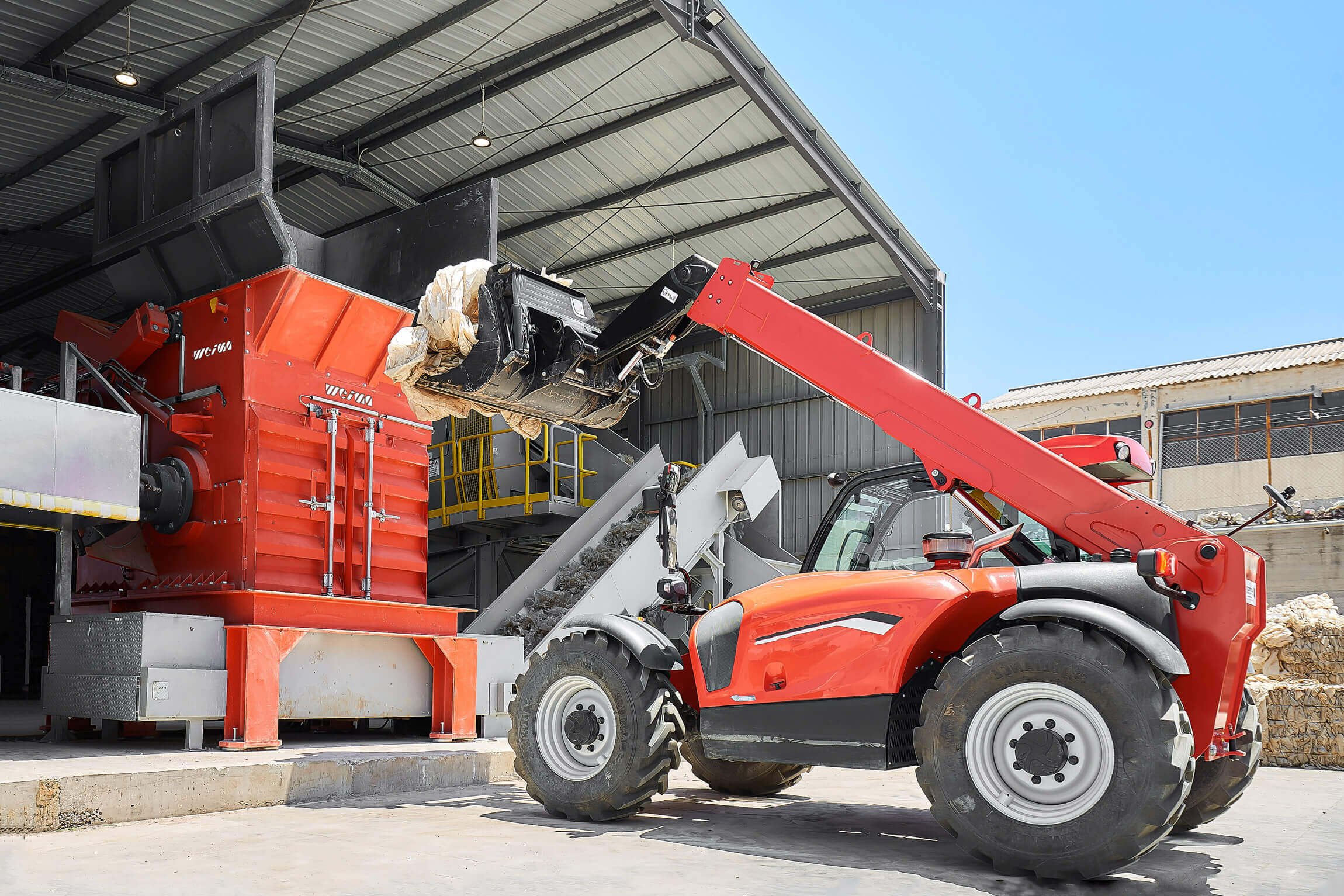 WEIMA PreCut single-shaft shredder for agricultural film, fed by a wheel loader