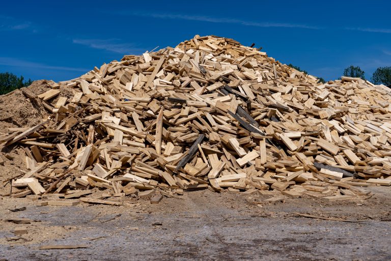A very large pile of various wood scraps and pieces of wood lying on a company site.