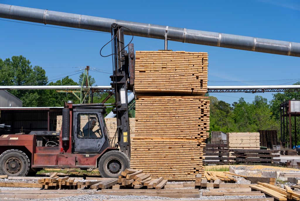 Stacked sawn timber is transported with a forklift and prepared for loading.