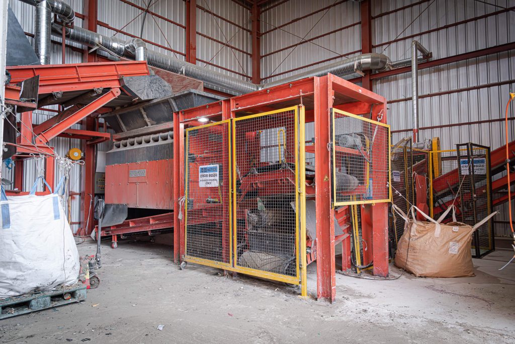 An orange shredder at a recycling company in South Korea shreds industrial waste.