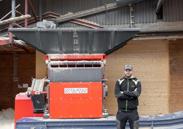 A red WEIMA S7.15 is standing in front of a building. A company employee stands next to it and looks into the camera.