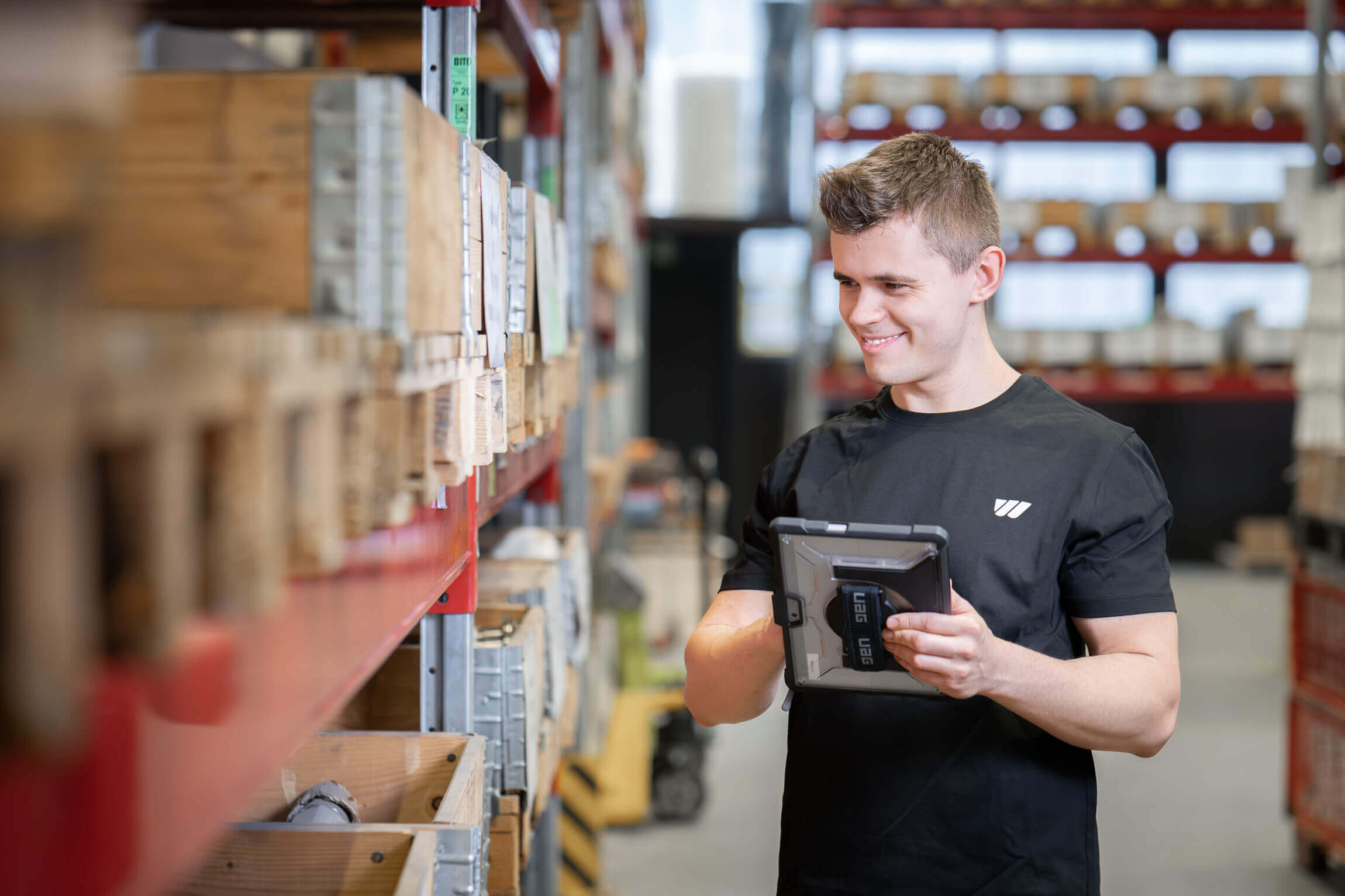 Warehouse employee with tablet in front of a shelf
