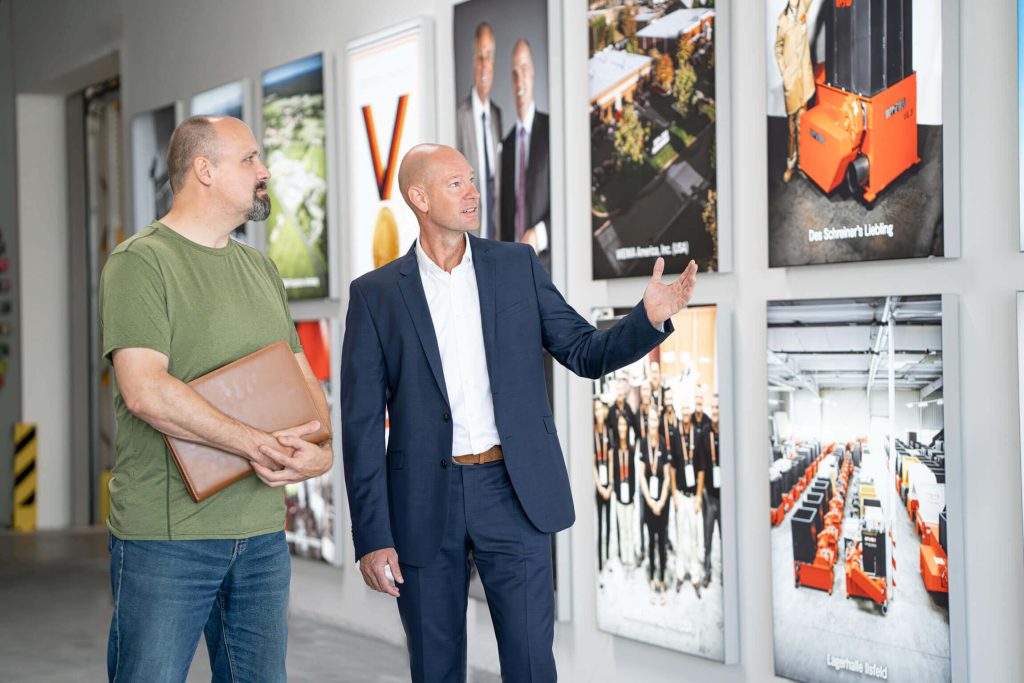 Kay Schulte at the WEIMA headquarters in front of photos on a white wall
