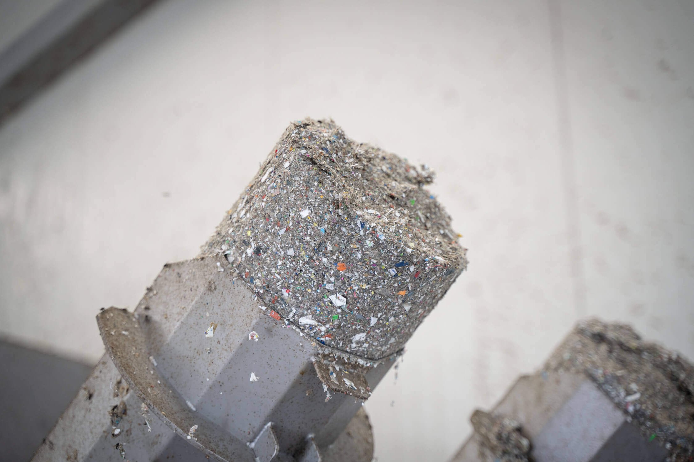 Dewatered and compressed gray lumps of plastic fine parts on the discharge pipes of a WEIMA C.200 Duo