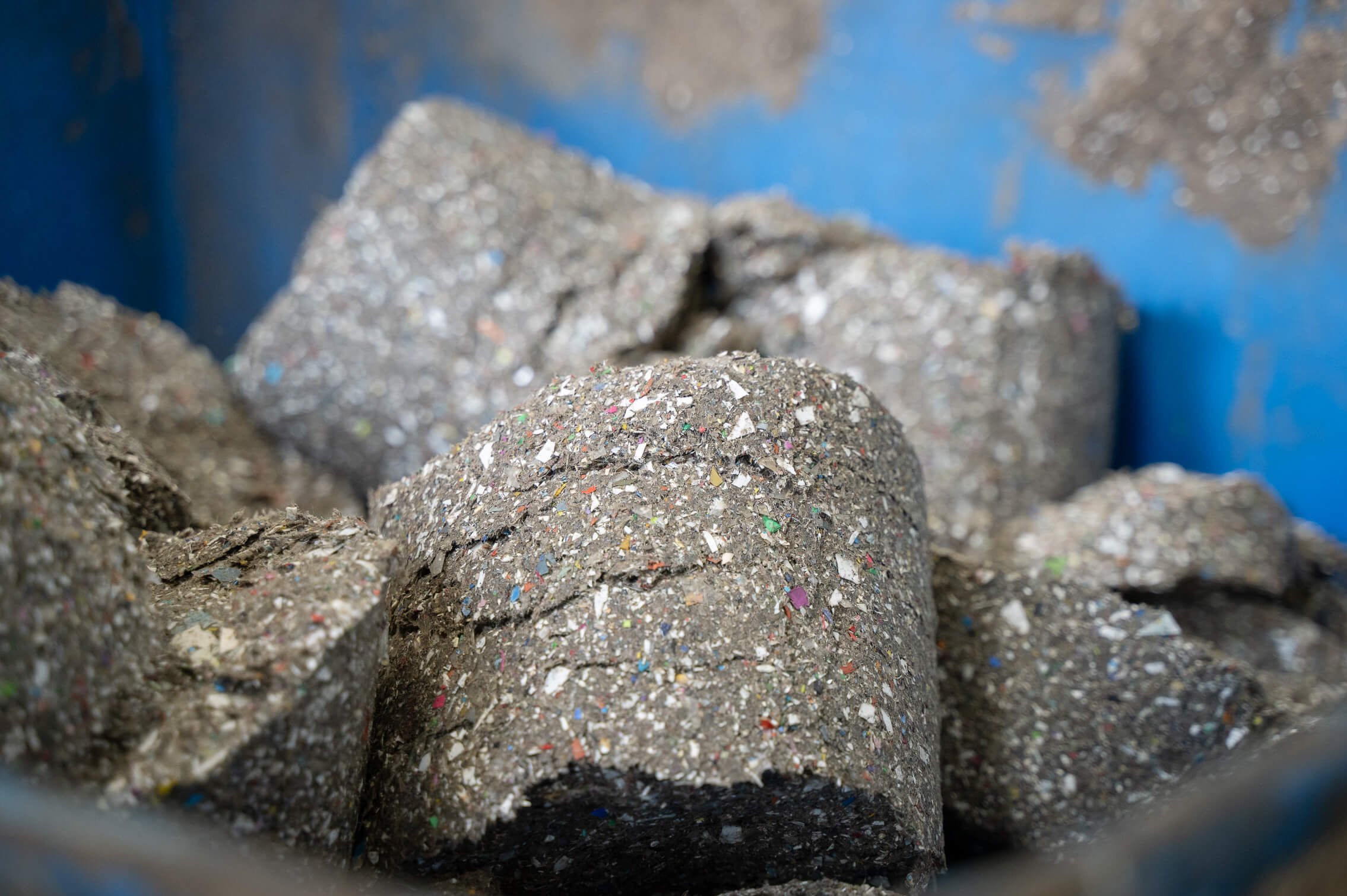 A pile of dewatered and compressed gray lumps of plastic fine parts