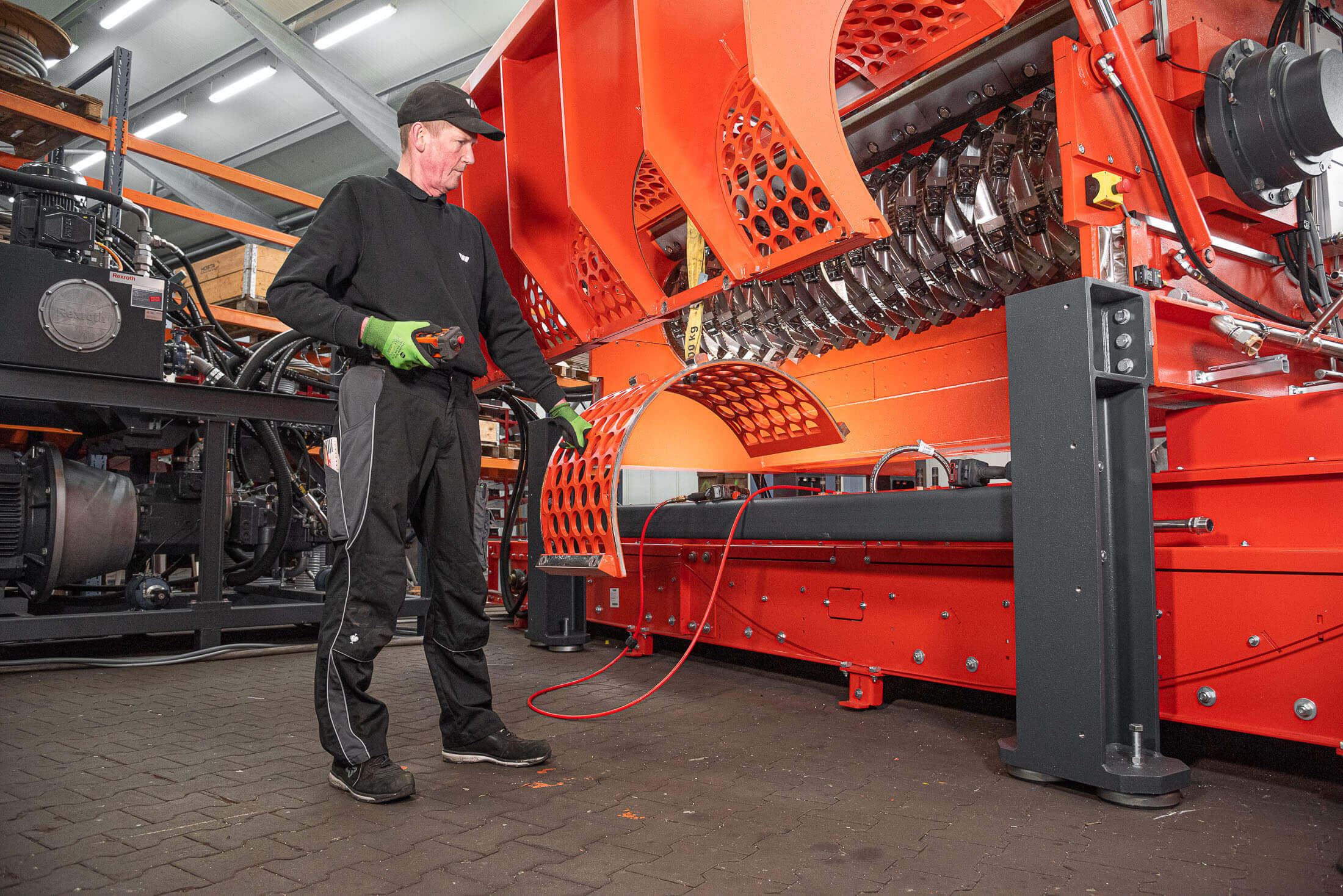 WEIMA employee working on an orange shredder with open screen basket