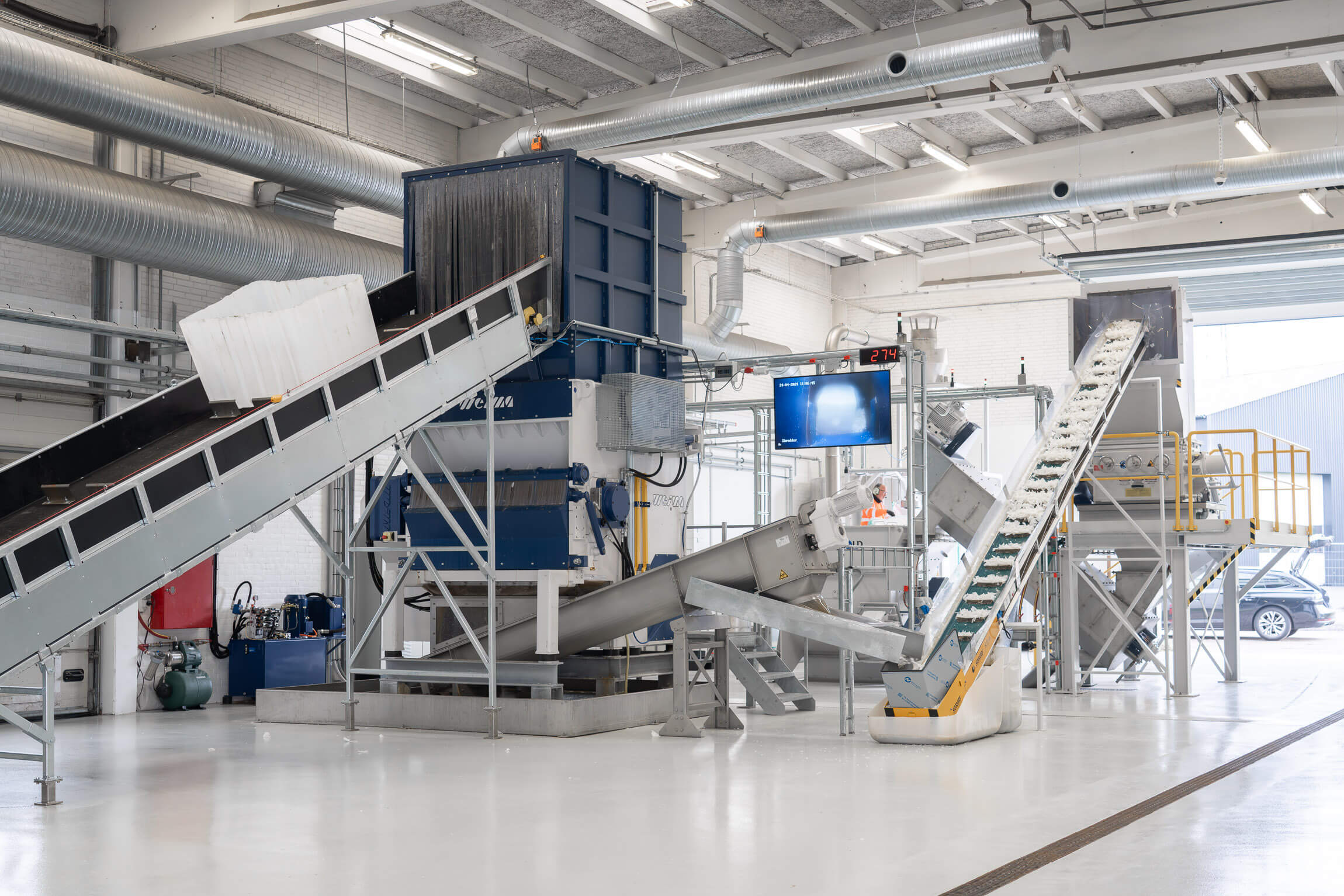 Several IBC containers are transported into the WEIMA shredder, in the background of the hall a granulator and a friction washing system