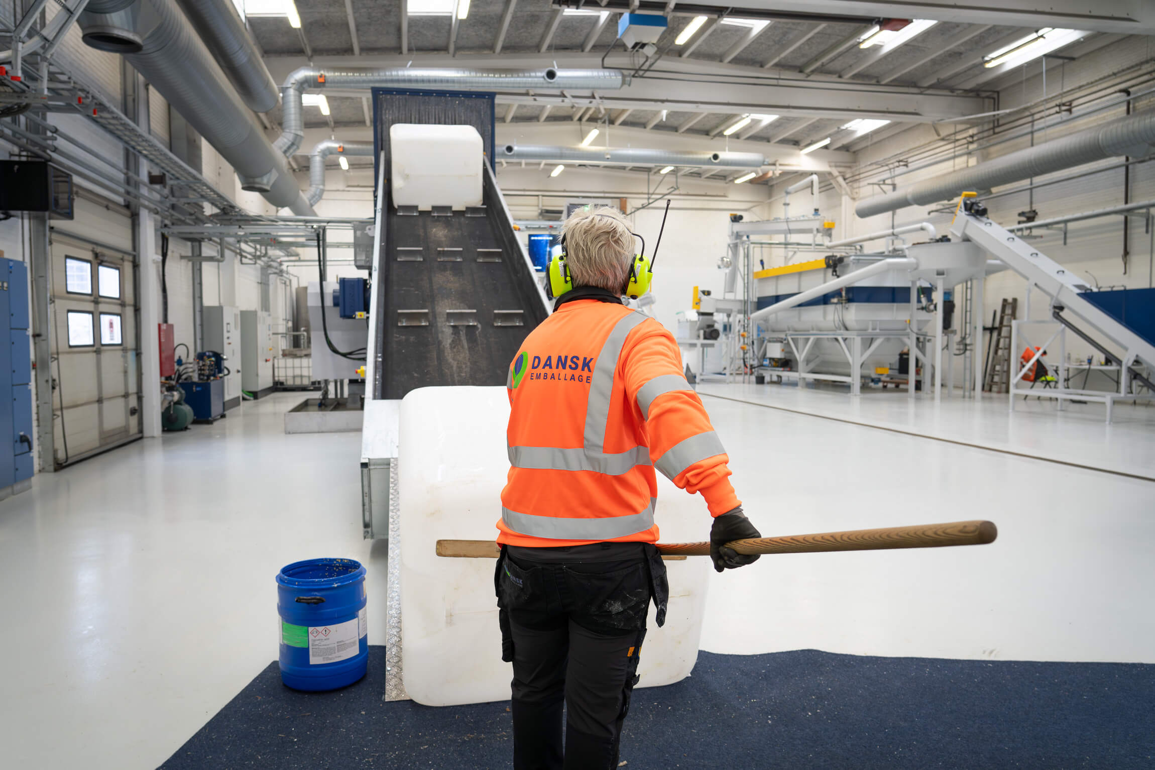 a Dansk Emballage employee pushes an IBC container onto a conveyor belt
