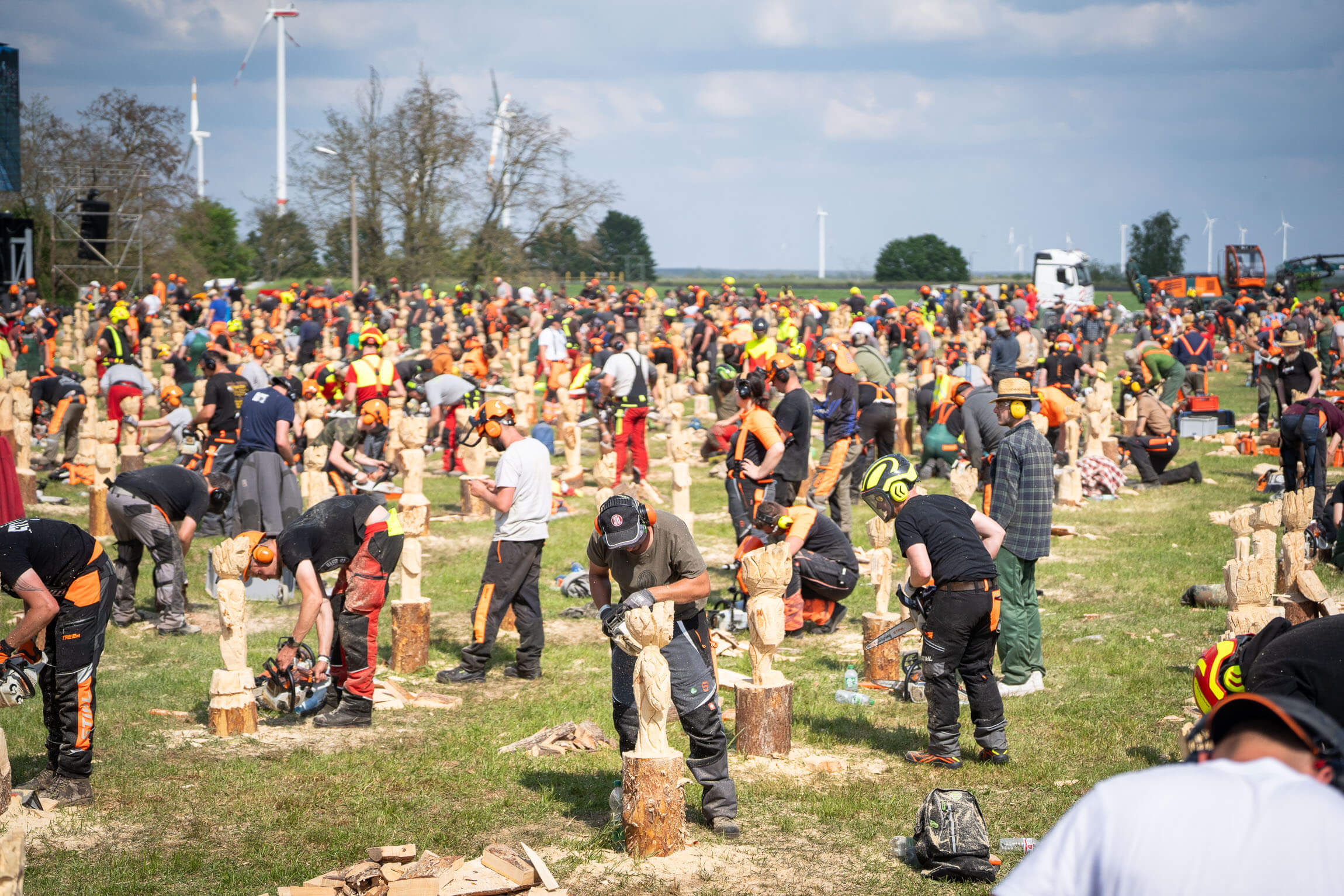 Lots of people with chainsaws carving a figure out of a block of wood