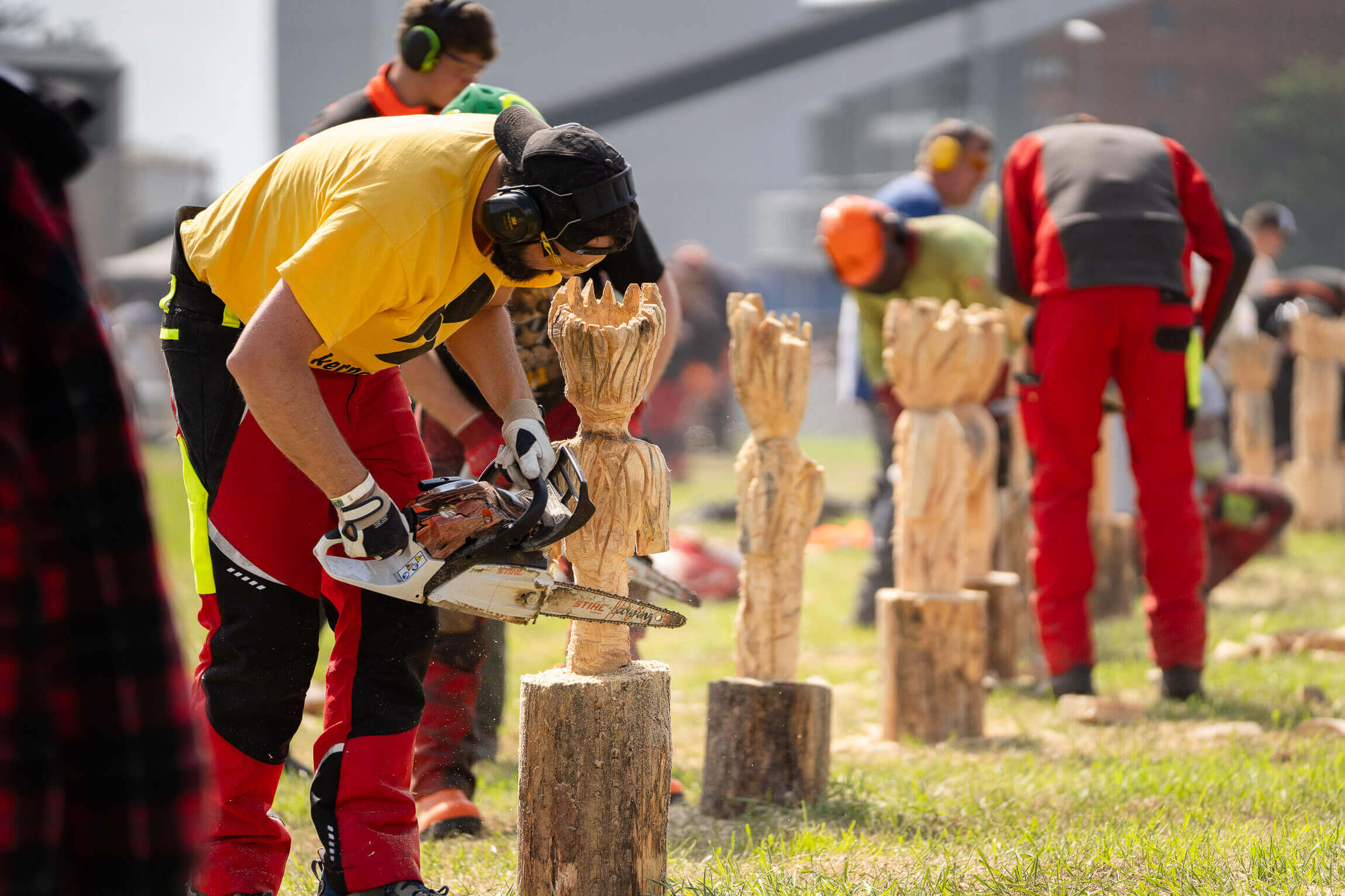 Several people saw sculptures out of wood
