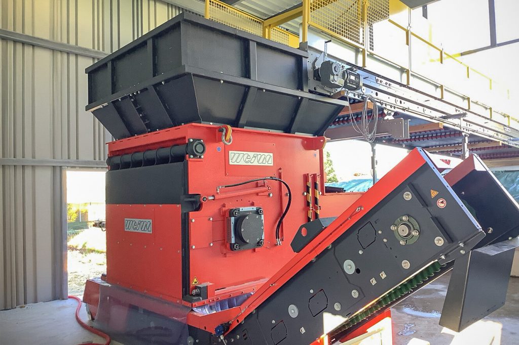 Orange shredder with discharge conveyor belt in a semi-open hall