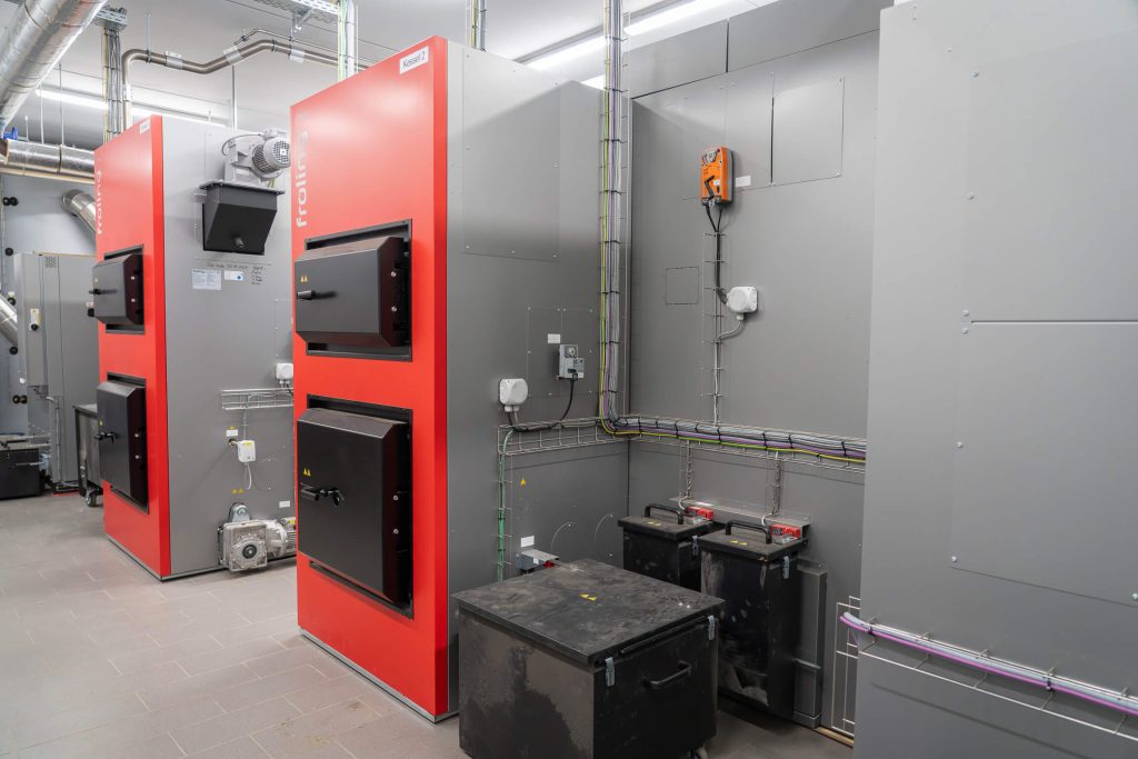 Two large wood chip heating boiler systems with red casings in the technical room of the Trier firewood plant.