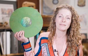 Anouk Rijnders from Record Industry holds a recycled green record in her hands and smiles