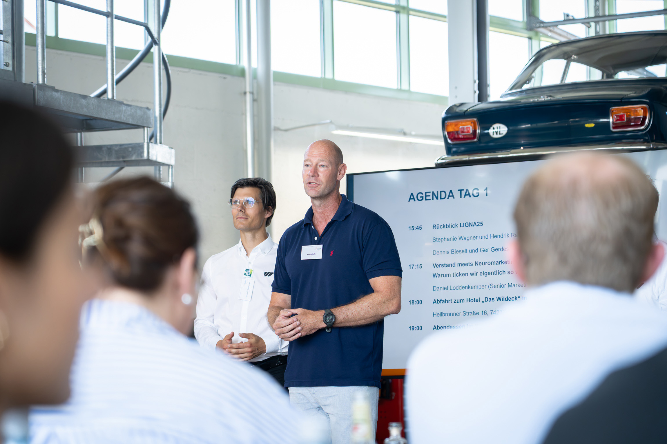 Two WEIMA employees stand at the front and welcome the guests