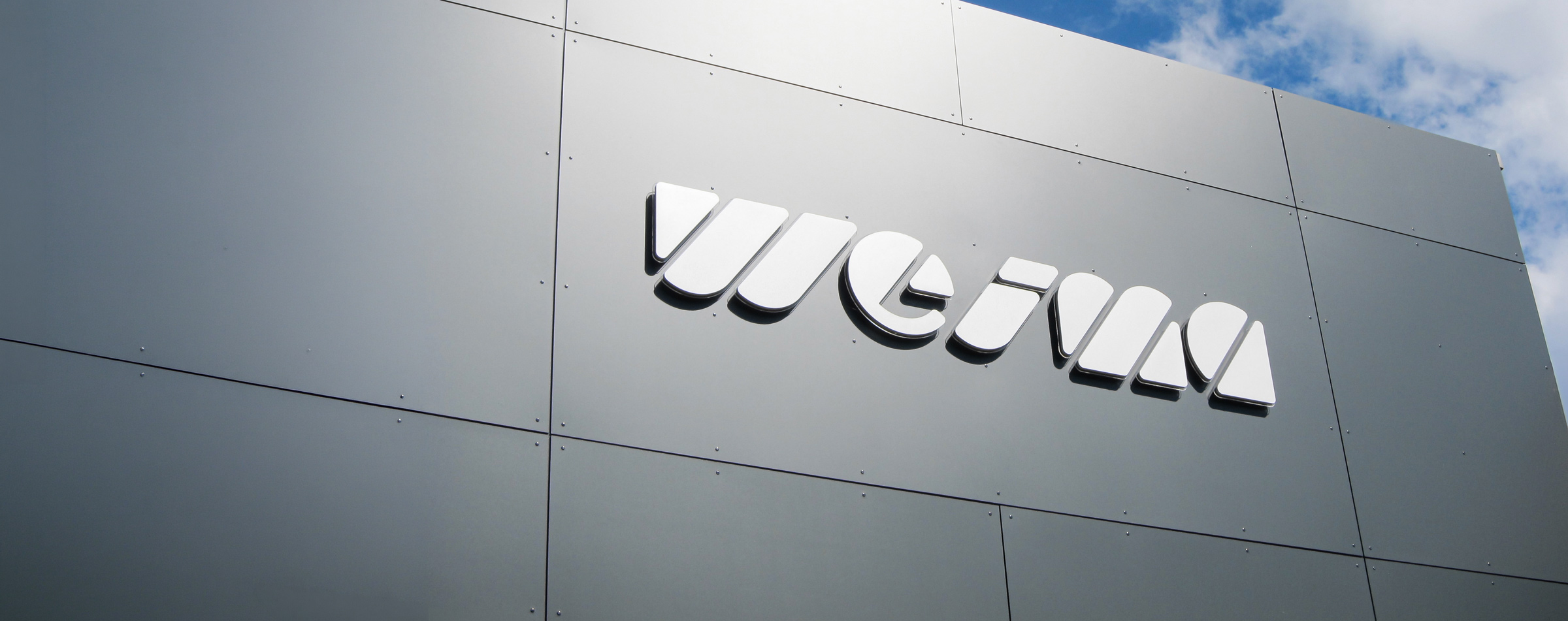 WEIMA logo on grey facade with blue sky in the background