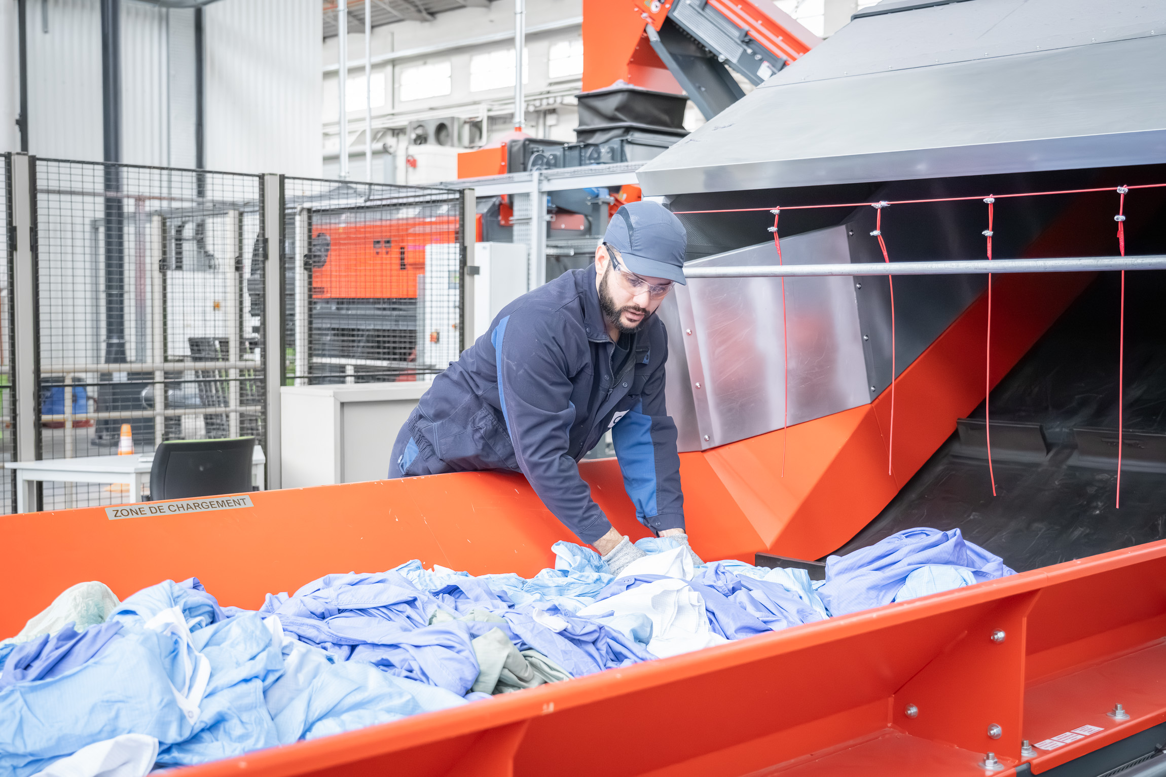 An employee places textiles on a conveyor belt